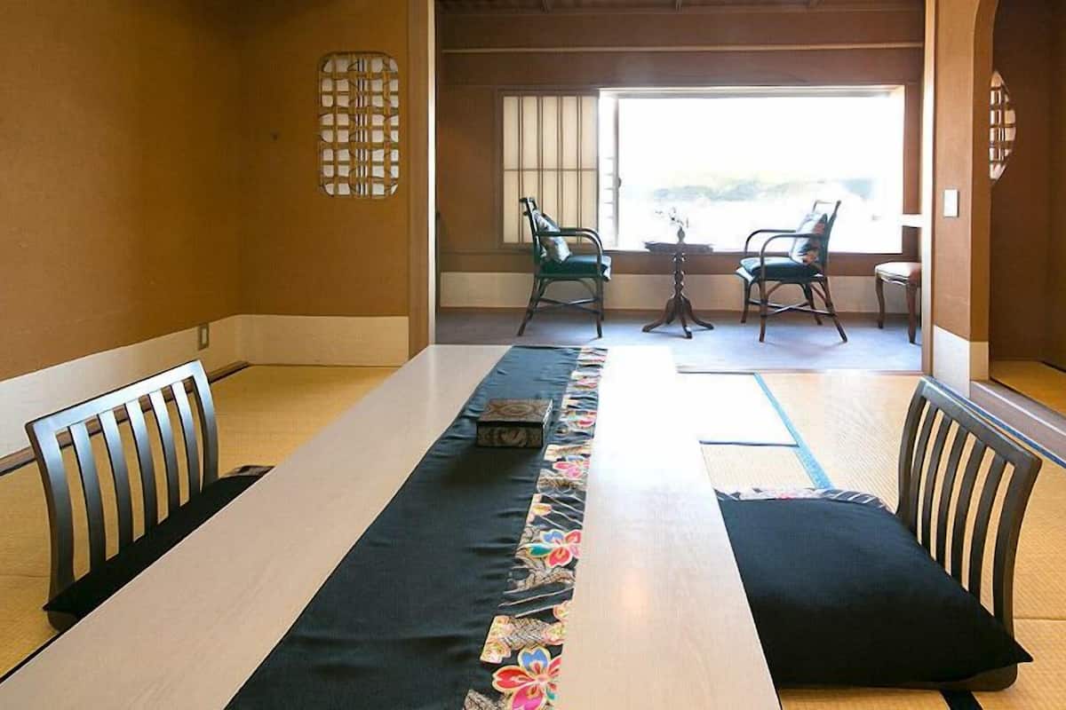 Una habitación japonesa tradicional con esteras de tatami, una mesa baja y puertas correderas shoji.