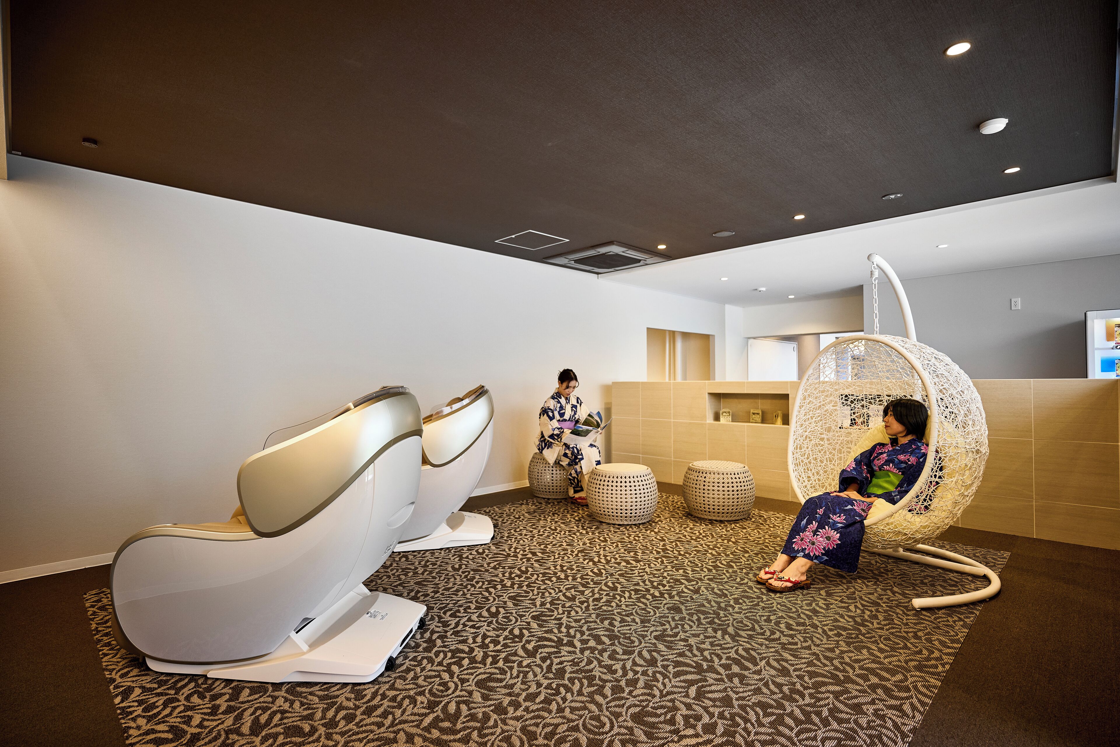 A modern spa area with massage chairs and a hanging chair.