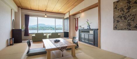 Una habitación japonesa tradicional con suelo de tatami, una mesa baja y vistas a las montañas a través de amplios ventanales.