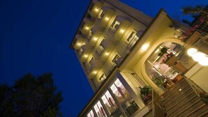A multi-story hotel with balconies, a staircase, and a well-lit entrance. - Hotel Alsen (Rimini)