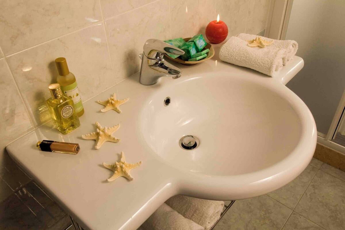 A bathroom sink with toiletries, a candle, and starfish decorations.