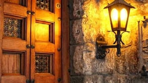 A wooden door with glass panels and a stone wall with a sign. - Palazzo Riario (Viterbo)