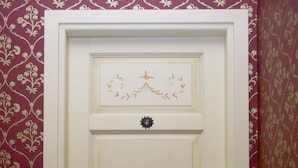A white door with a gold handle and a decorative emblem. - Palazzo Riario (Viterbo)
