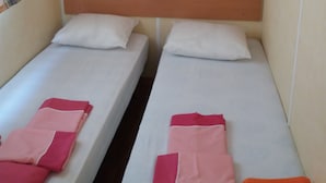 Una habitación con dos camas individuales, cada una con cabecero de madera y ropa de cama blanca.