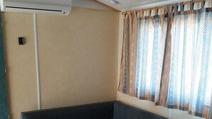 Una habitación con una mesa de madera, un sofá azul y una ventana con cortinas estampadas.