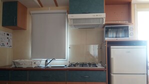 Una cocina compacta con estufa a gas, microondas y refrigerador.