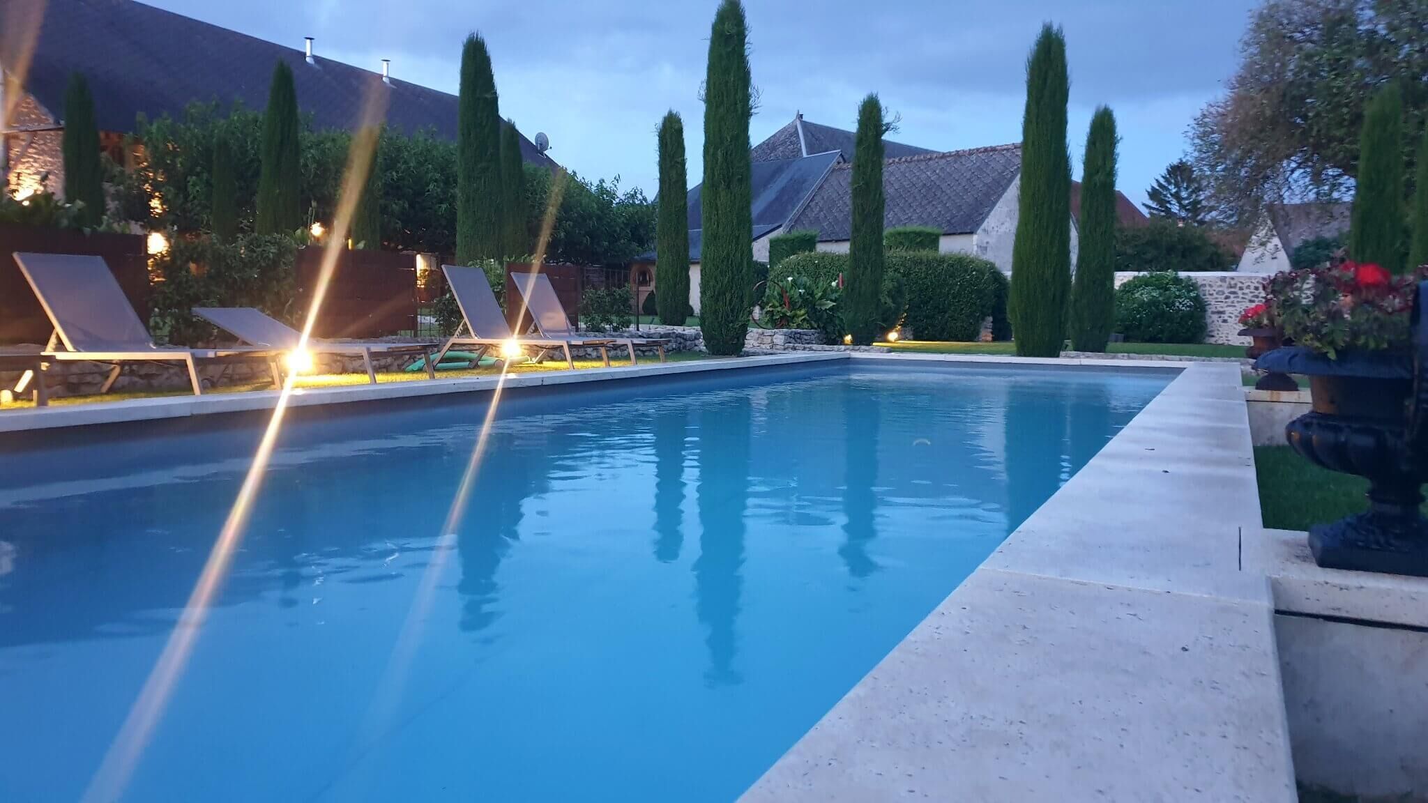 Une piscine avec des chaises longues et un mur en pierre.