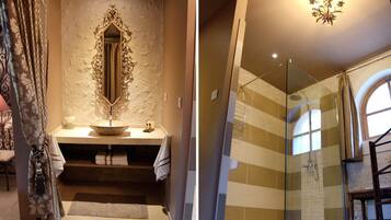 A bathroom with a stone sink, a mirror with ornate frame, and a shower with a glass door.
