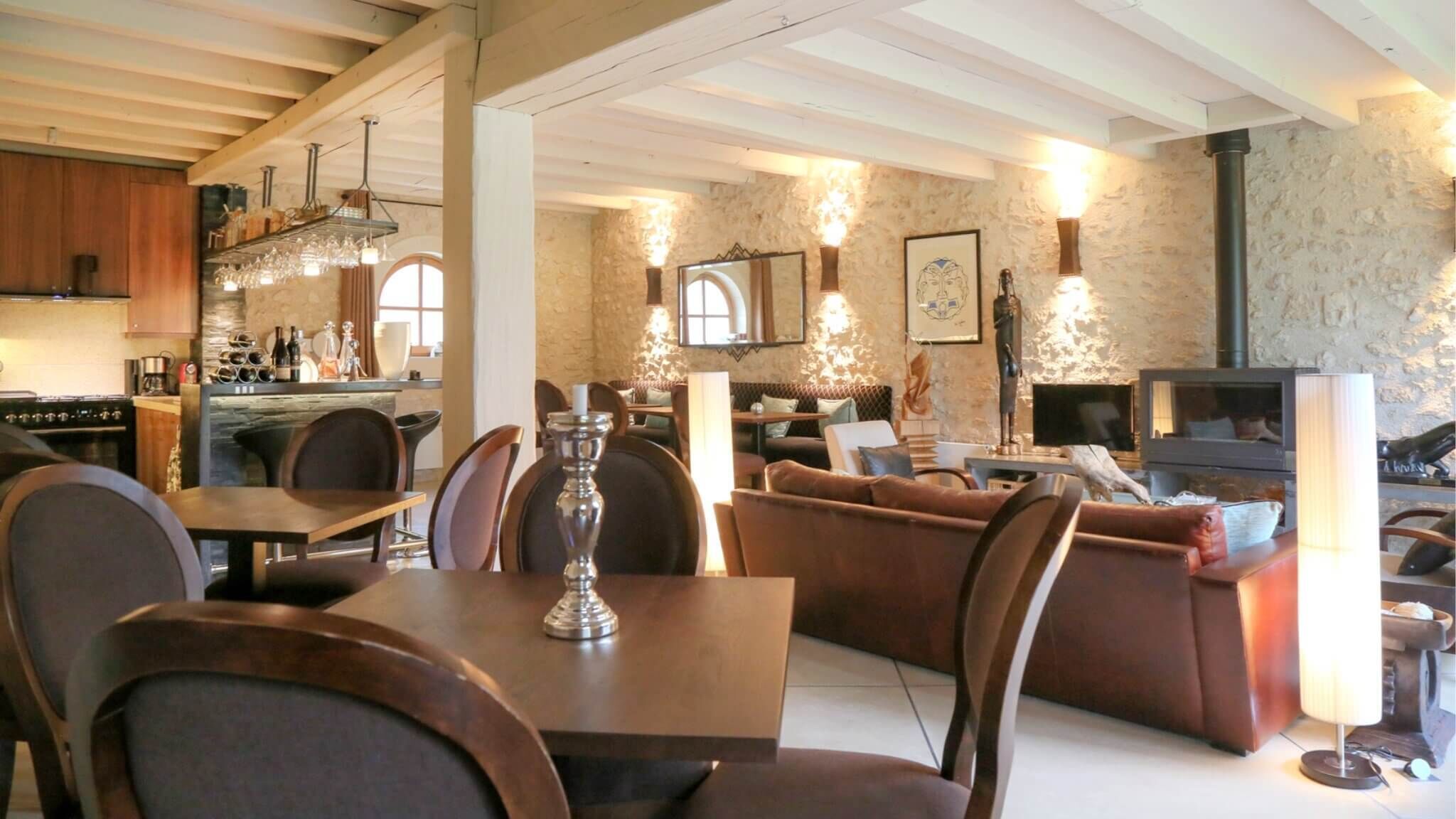 A spacious living area with a fireplace, comfortable seating, and a kitchen in the background.