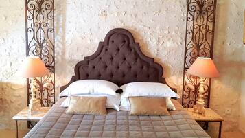 Uma cama com cabeceira estofada, duas luminárias de cabeceira e uma parede texturizada.
