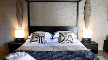 Un lit à baldaquin avec des coussins à motifs, deux lampes de chevet et une tête de lit sombre.