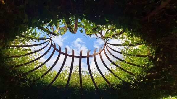 Estrutura metálica circular rodeada por vegetação exuberante e céu limpo.