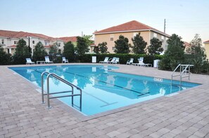 A rectangular swimming pool with a metal ladder and railings, surrounded by lounge chairs and a paved deck. - Crestwynd #1 - 3 Bed 3 Baths Townhome (Kissimmee)