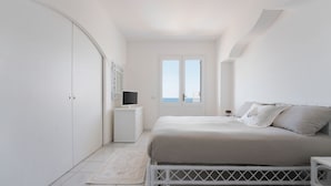 A bedroom with a bed, a wardrobe, a small bedside table, and a view of the sea through a door. - Villa del Sole (Massa Lubrense)