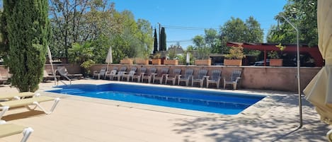Una piscina con sillones de descanso y una pérgola.