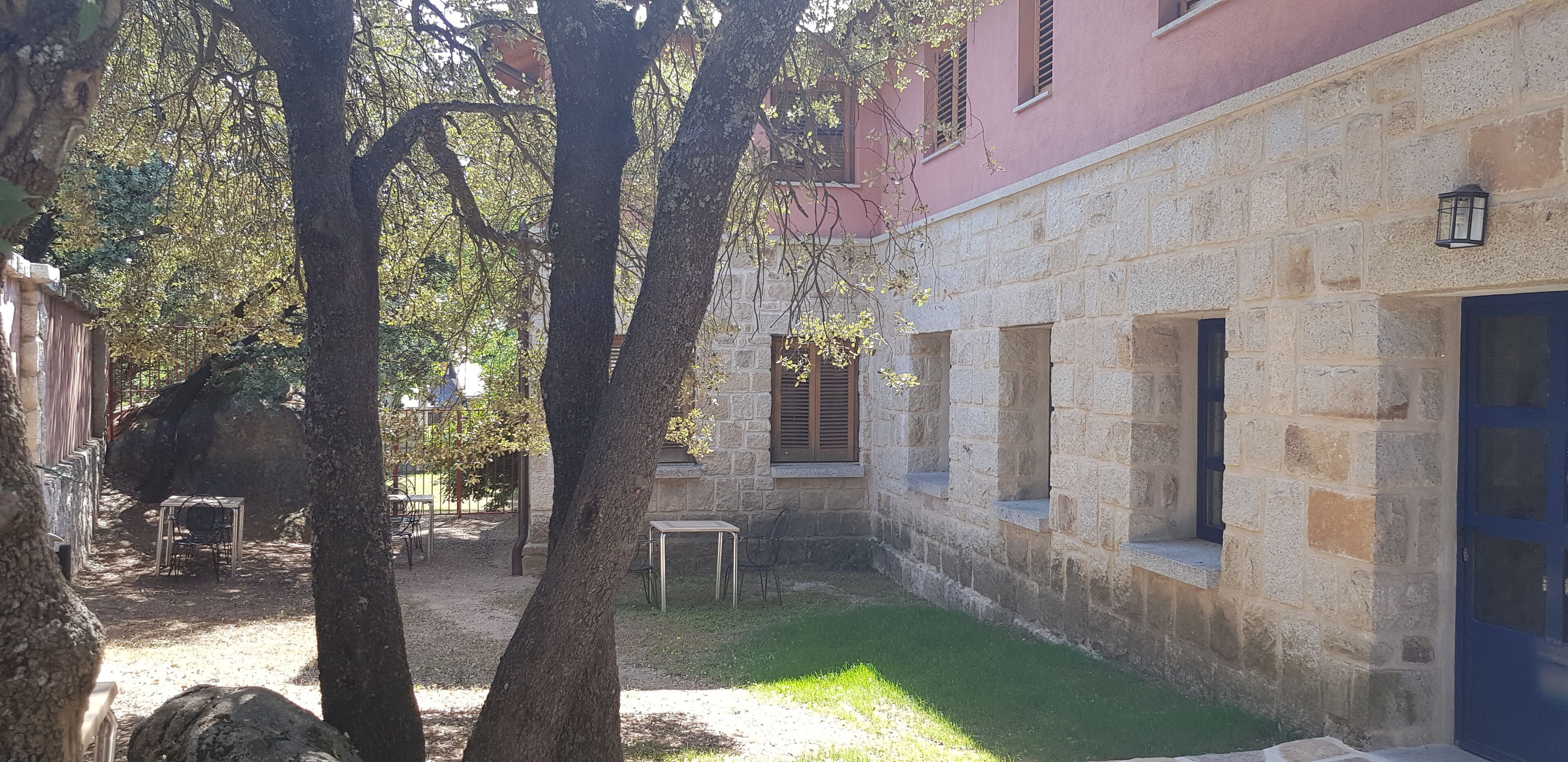 A courtyard with stone walls, a blue door, and outdoor seating.