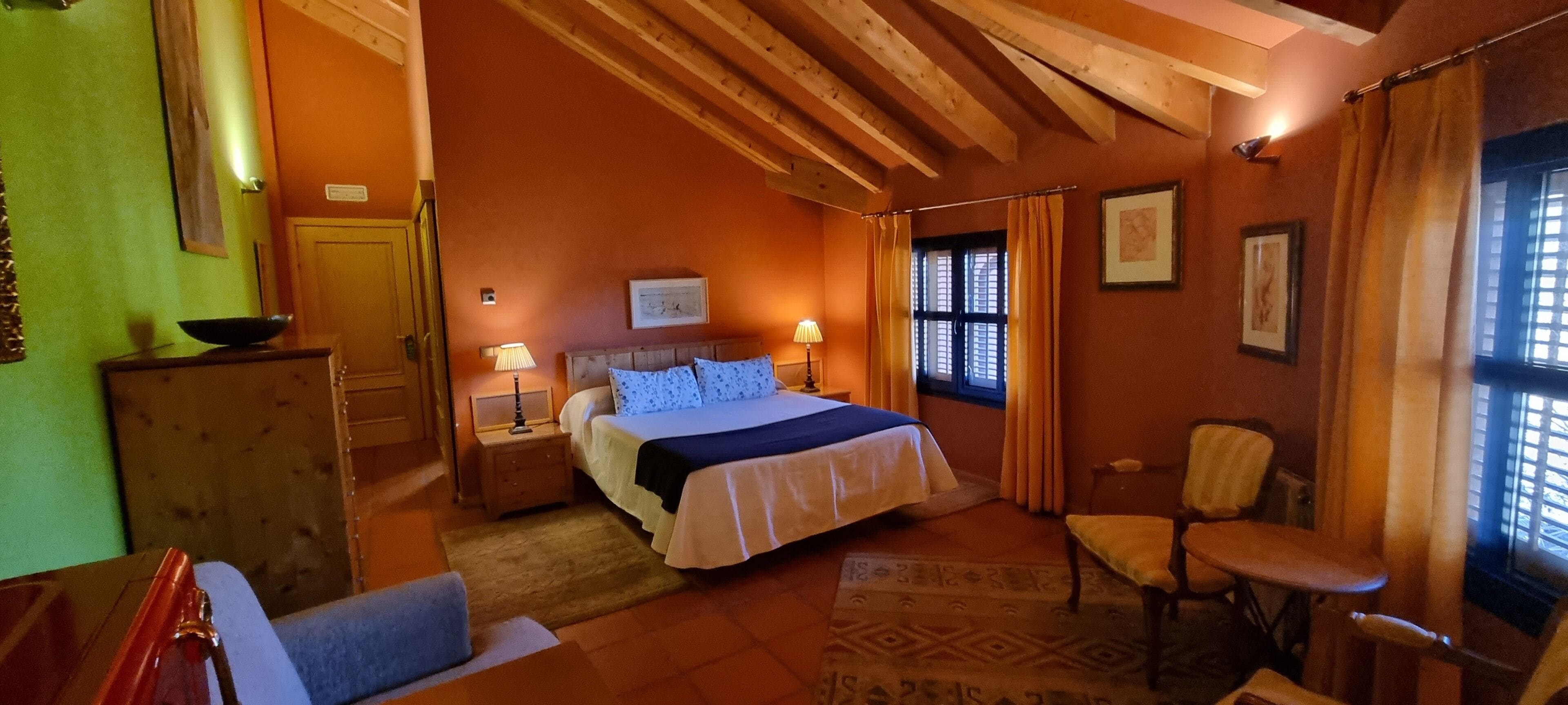 Una camera accogliente con un letto, comodini, una poltrona e una finestra con tende.