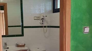 Ein Badezimmer mit weißem Waschbecken, Holzschrank, Toilette und einer grünen Wand.
