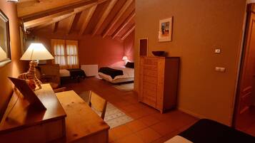 Una habitació acollidora amb sostre de fusta, un llit, un armari i un escriptori amb una làmpada.