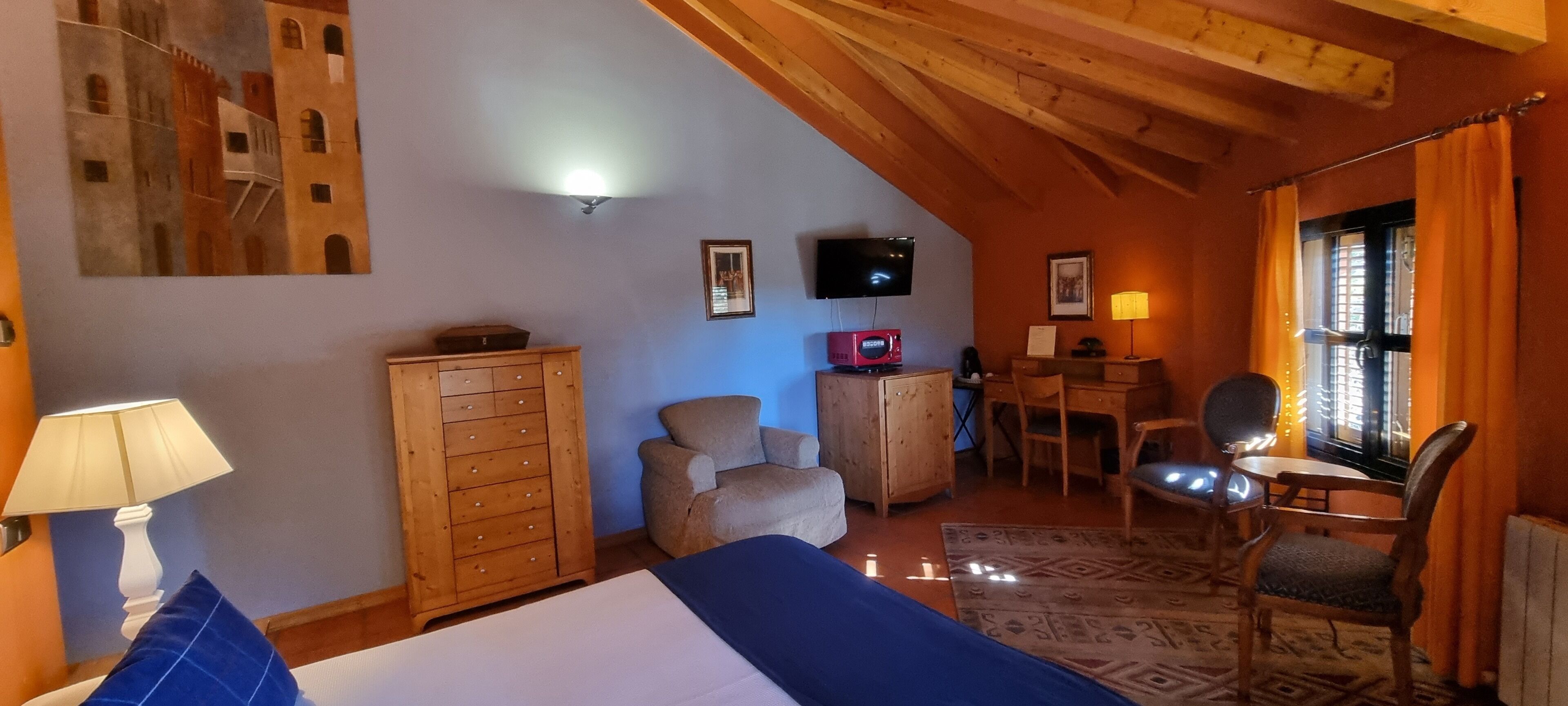 Un dormitorio con cama, cómoda de madera, escritorio, silla y televisor.
