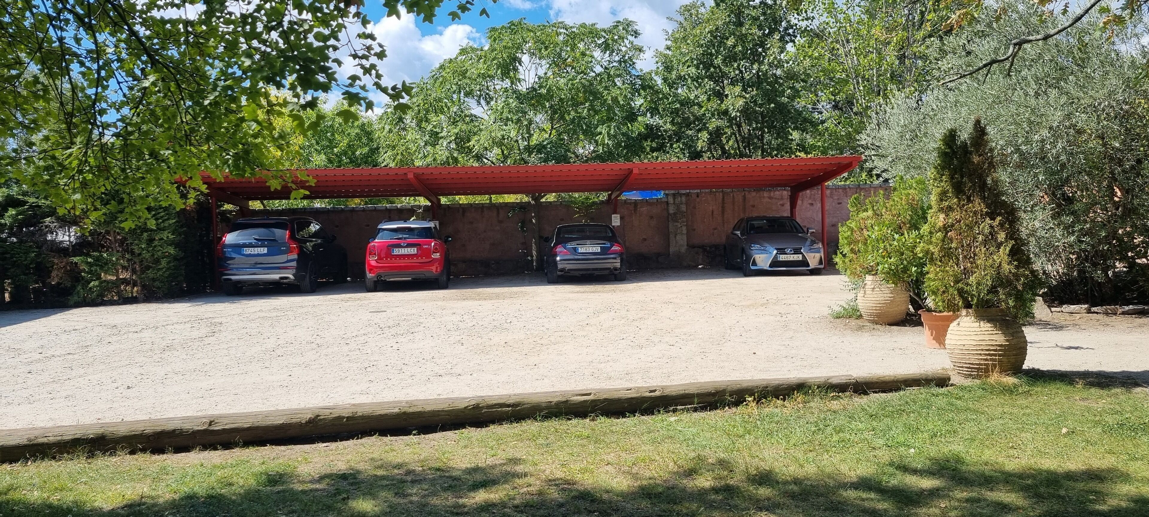 Un'area di parcheggio coperta con tre automobili sotto un tetto rosso.