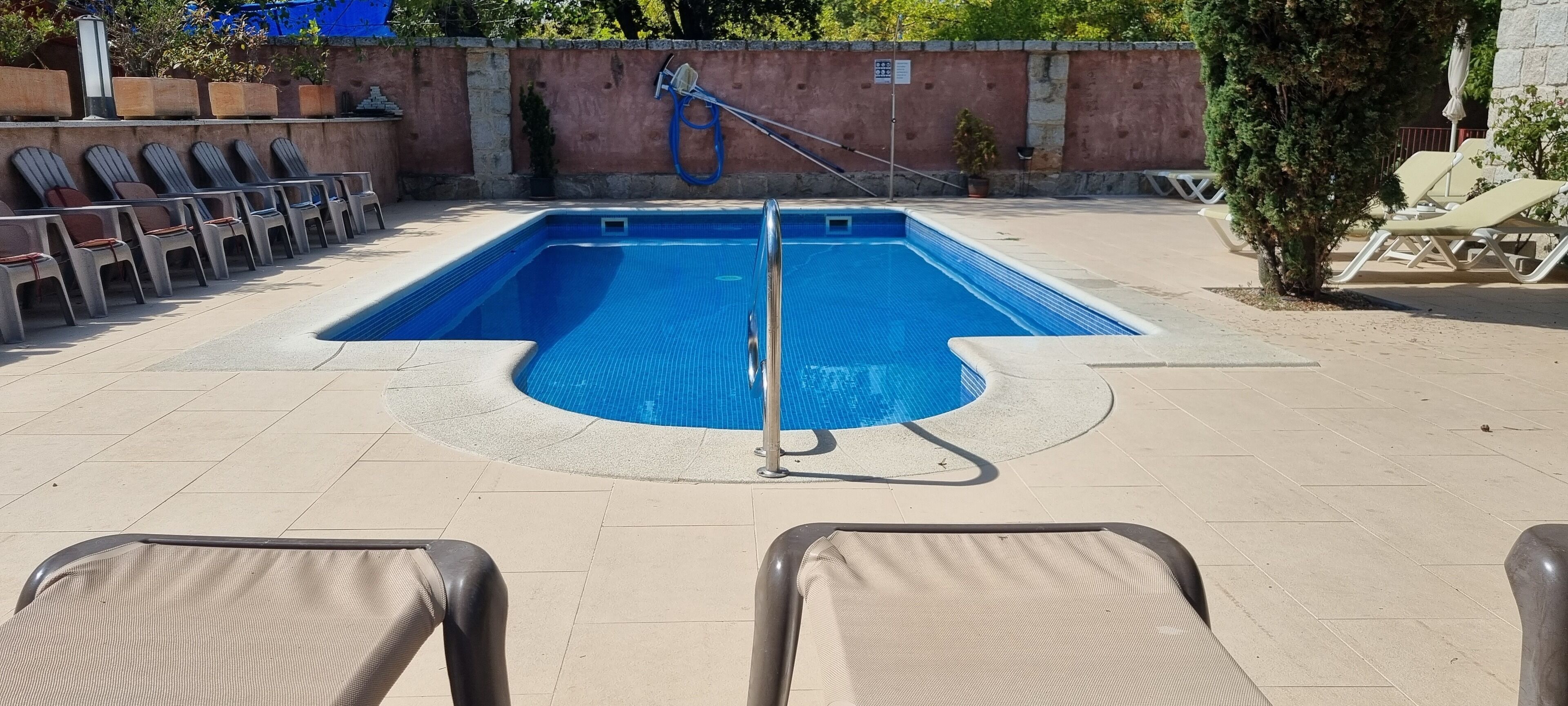 A swimming pool with lounge chairs and a hose for cleaning.