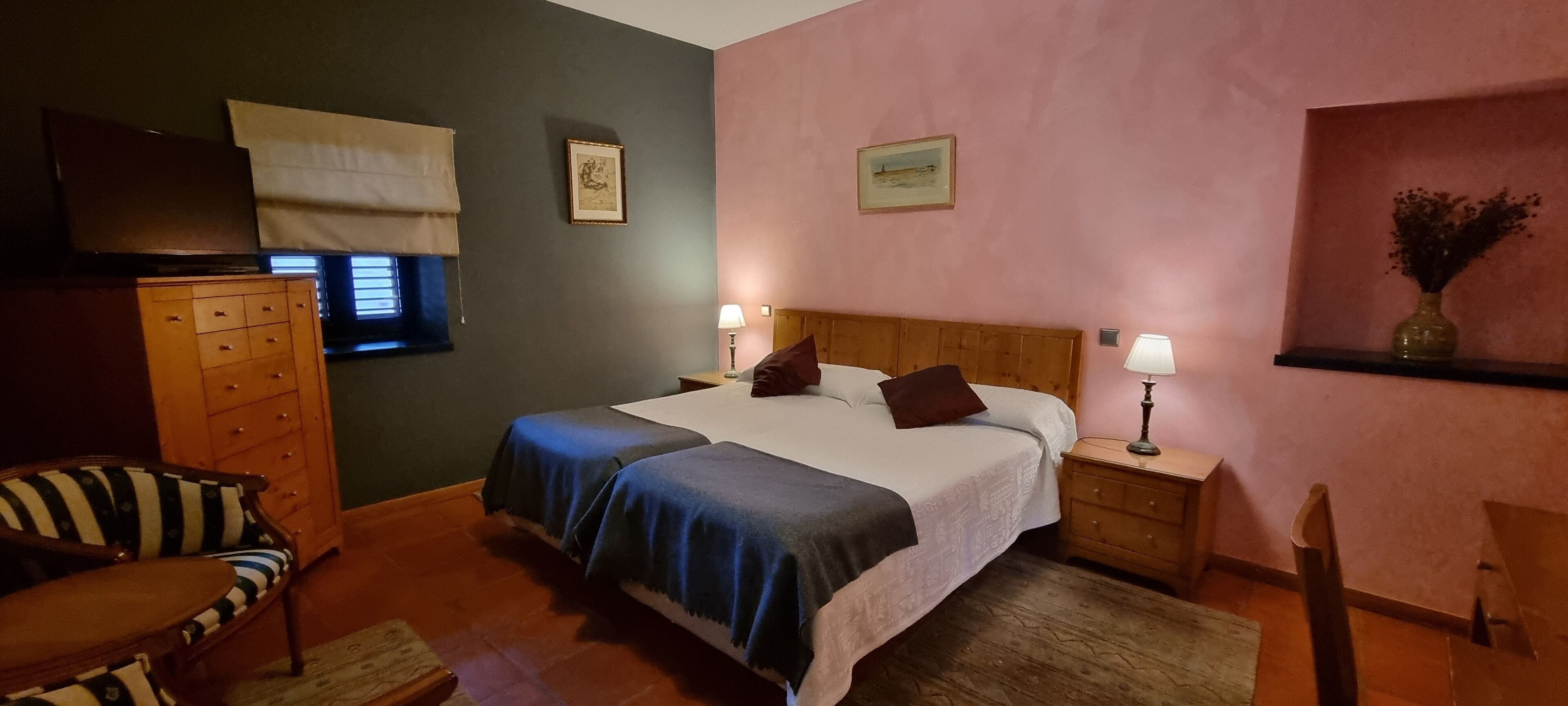 A bedroom with a bed, nightstands, a dresser, a chair, and a television.