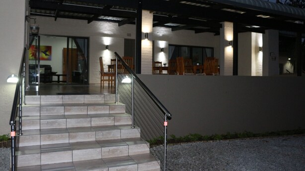 A modern building with a covered outdoor area, steps leading to a balcony, and outdoor seating. - Hummingbirds Nest Guesthouse (Mbombela)
