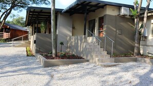 A modern building with a covered porch, a staircase leading to the entrance, and a gravel driveway. - Hummingbirds Nest Guesthouse (Mbombela)
