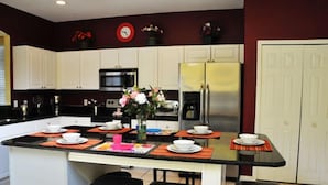 A modern kitchen with white cabinets, stainless steel appliances, and a central island with seating. - Lake Berkley - 7 Bed 5 Baths Villa (Kissimmee)