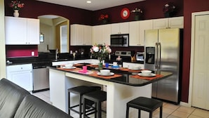 A modern kitchen with white cabinets, stainless steel appliances, and a central island with bar stools. - Lake Berkley - 7 Bed 5 Baths Villa (Kissimmee)