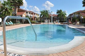 A rectangular swimming pool with a metal ladder, surrounded by lounge chairs and palm trees. - Lake Berkley - 7 Bed 5 Baths Villa (Kissimmee)