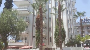 A multi-story hotel with balconies, palm trees, and outdoor seating.