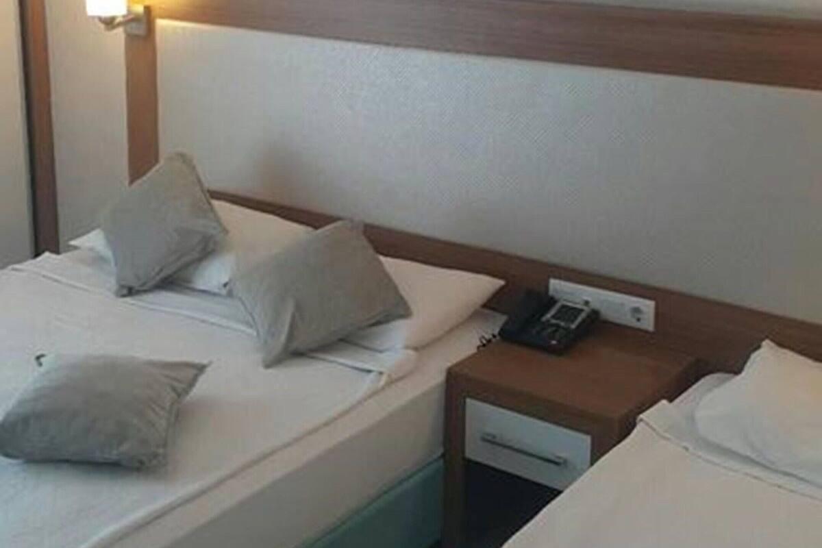 Een hotelkamer met twee bedden, een nachtkastje met telefoon en een schilderij aan de muur.