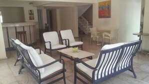 A spacious living area with a sofa set, a small table, and a staircase leading to another level.