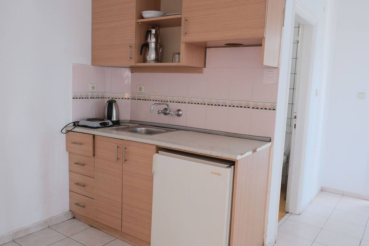 Een kleine keuken met een spoelbak, koffiezetapparaat en broodrooster op het aanrecht.