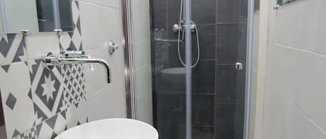 A bathroom with a large white sink, a toilet, and a glass-enclosed shower area.