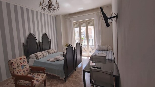 Un dormitorio con cama, una silla, un escritorio y una araña.