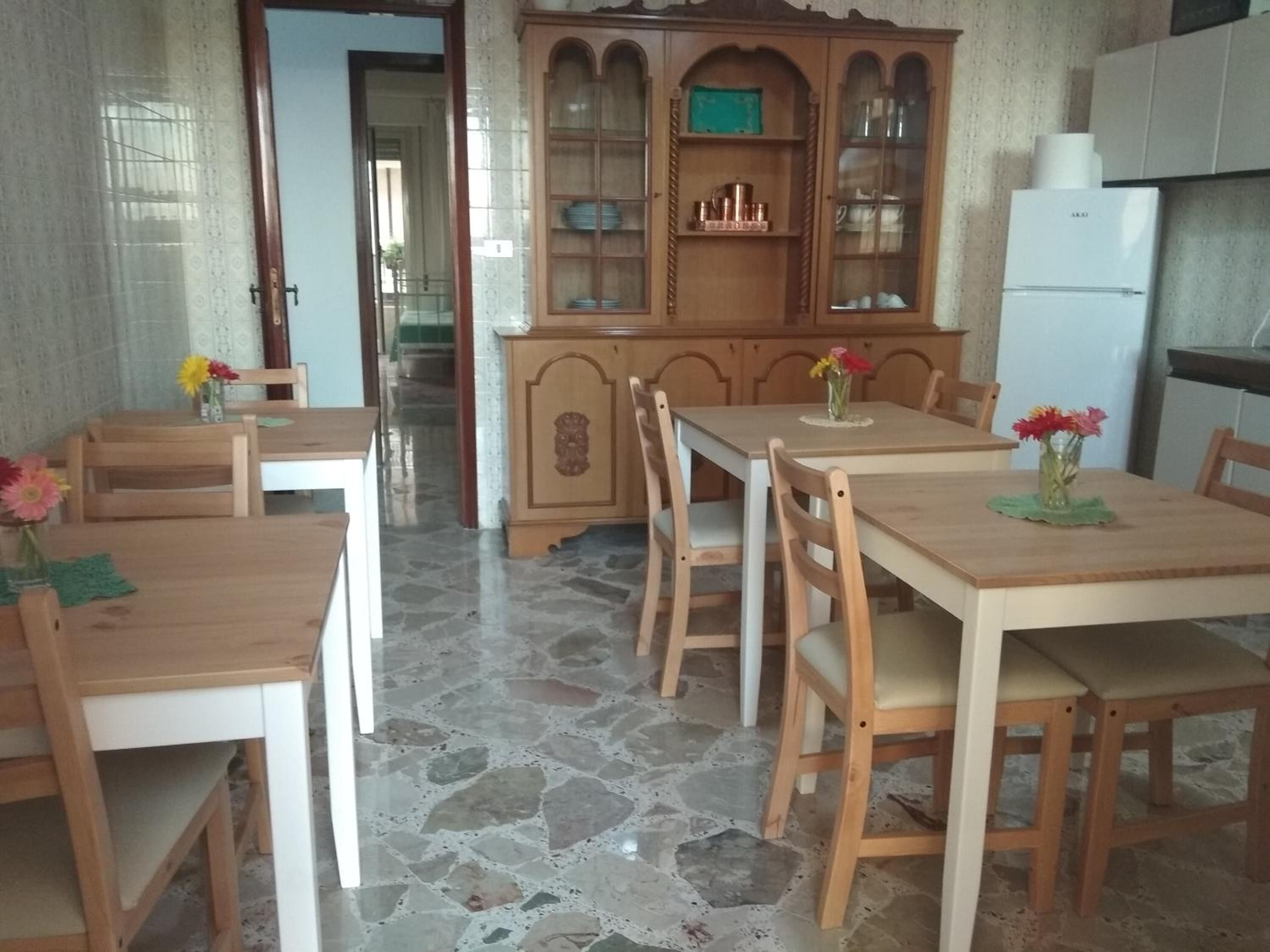 Ein Essbereich mit Holztisch und Stühlen, einer Schranke mit Glastüren sowie einem Kühlschrank.