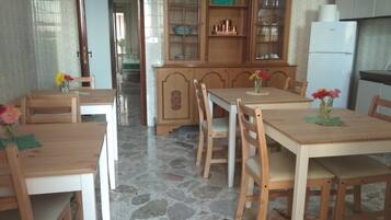 Ein Essbereich mit Holztisch und Stühlen, einer Schranke mit Glastüren sowie einem Kühlschrank.