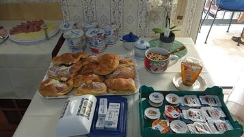 En frukostbuffé med bakverk, yoghurt och ett urval av pålägg.