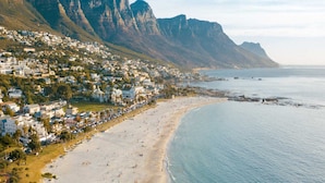 A coastal town with a beach, houses, and mountains in the background. - Luxury on the Beach, Lagoon Beach (Cape Town)