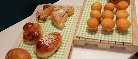 A table with various pastries and a bowl of fruit.