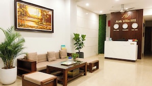 A reception area with a sofa, coffee table, and potted plants. - Anh Villa Hotel (Da Nang)