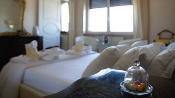 Een hotelkamer met een bed, nachtkastje en een raam met gordijnen.