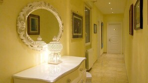 A hallway with a white vanity, a large ornate mirror, and a lit decorative lamp.