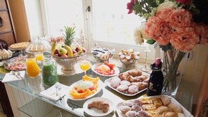 A breakfast buffet with various food items and beverages on a glass table.