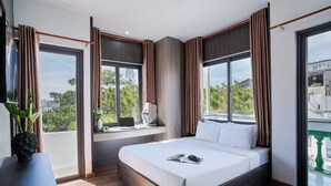A modern hotel room with a large bed, a desk with a laptop, and a view of the outdoors. - ELC Luxury Da Lat Hotel & Apartment (Xuan Huong - Da Lat)