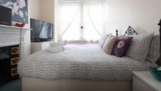 Une chambre à coucher bien rangée, avec un lit, une télévision et une cheminée.
