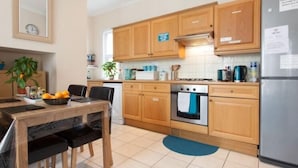 Une cuisine moderne avec des meubles en bois, un réfrigérateur en acier inoxydable et un coin repas comprenant une table et des chaises.